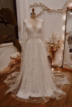 a white wedding dress on display in front of a mirror and other items behind it