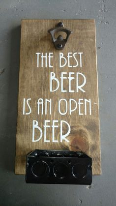 a wooden sign that says the best beer is an open beer with two keys hanging from it