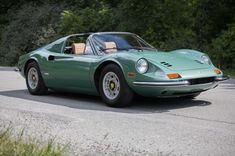 a green sports car driving down a road