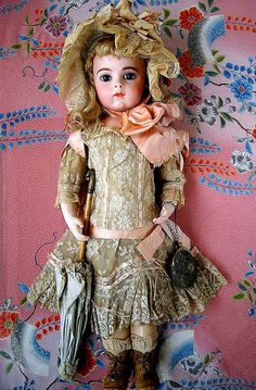 an antique doll is posed on a floral background