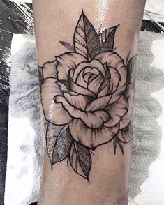 a black and white rose tattoo on the leg