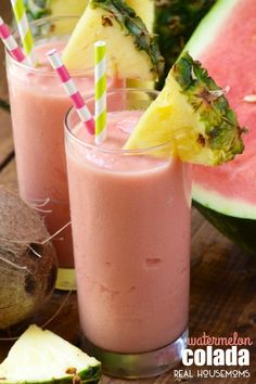 two glasses filled with pink smoothie next to pineapples and watermelon