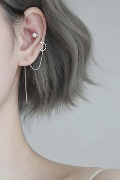 a woman with grey hair wearing a pair of ear piercings and a silver chain