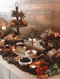 a table topped with lots of different types of foods and desserts next to candles