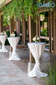 two tables with white tablecloths and flowers on them in front of a building