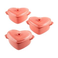 three pink heart shaped casserole dishes on a white background