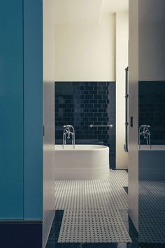 a bathroom with black and white tiles on the floor, tub and sink are seen through an open door