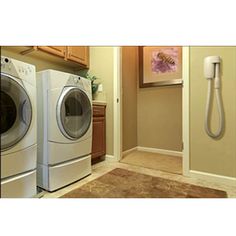 a washer and dryer in a small room next to a door with a phone on the wall