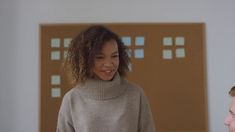 a man and woman standing next to each other in front of a wall with squares on it