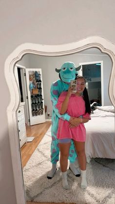 a woman taking a selfie in front of a mirror with a stuffed monster on it