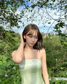 a young woman in a green dress posing for the camera with her hand on her head