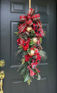 a christmas wreath hanging on the front door with bells and pineconis attached to it