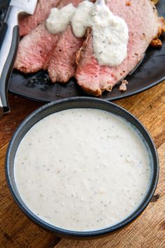 a plate with some meat on it next to a bowl of ranch dressing and a fork