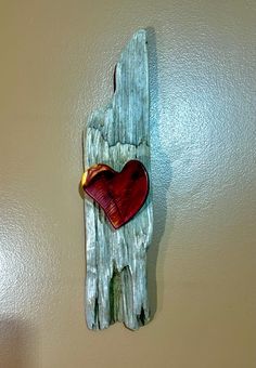 a piece of wood with a heart on it hanging from the side of a wall