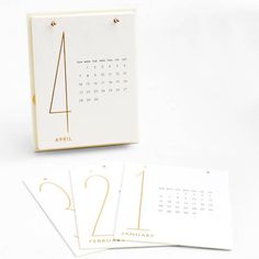 three calendars with gold numbers on them sitting next to each other in front of a white background