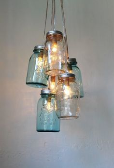 mason jar chandelier hanging from the ceiling with lights in it and jars on top