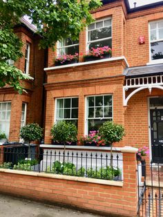 a red brick house with flower boxes on the front and side windows, along with wrought iron railings