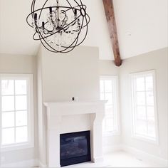 a chandelier hanging from the ceiling in a living room with white walls and windows