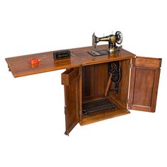 an old sewing machine sitting inside of a wooden cabinet next to a red object on top of it