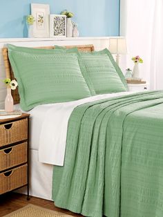 a bed with green bedspread and white sheets