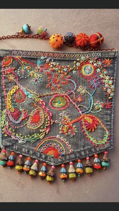 an embroidered purse with beads and chains hanging from it