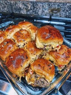 a glass baking dish filled with sliders on top of an oven burner next to a granite countertop