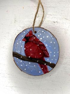 a wooden ornament with a red cardinal painted on it