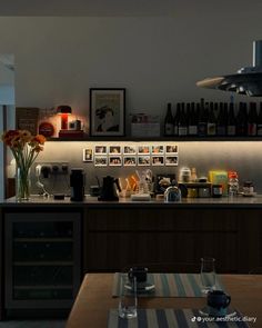 a dimly lit kitchen with wine bottles on the counter and flowers in vases next to it