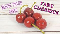 four cherries on a white wooden surface with the words make your own fake cherries