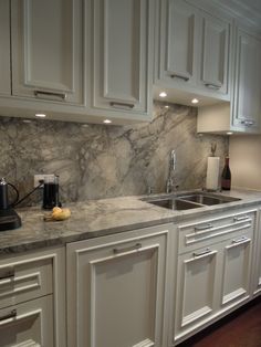 a kitchen with marble counter tops and white cabinets