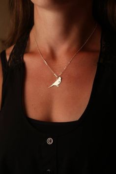 a woman wearing a necklace with a small bird on it's back and the word love