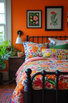 a bedroom with an orange wall and floral bedding