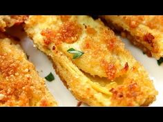 some fried food on a white plate with parmesan cheese and green garnish