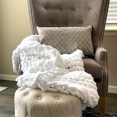 a chair with a blanket on it and a footstool in front of it