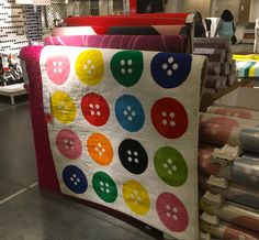 there is a large quilt on display in the store with many different colors and sizes