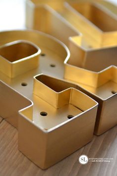 four gold trays sitting on top of a wooden table with holes in the middle