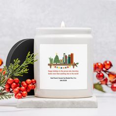 a white candle sitting on top of a table next to some red berries and greenery