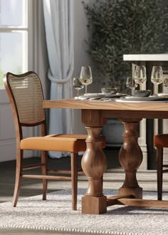 a wooden table with two chairs and a wine glass on top of it in front of a window