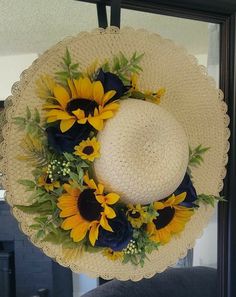 a white hat with sunflowers and blue flowers on it hanging from a door