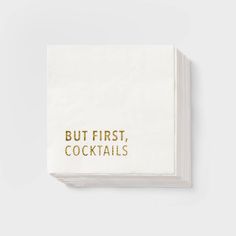 a napkin with the words but first, cocktails printed in gold foil on it