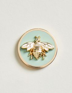 a yellow and blue bee pin sitting on top of a white table next to a wall