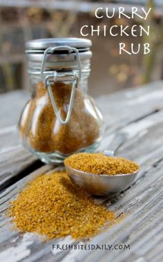 curry chicken rub in a glass jar next to a metal spoon on a wooden table