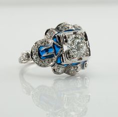 This vintage ring is crafted in solid 14K White Gold (carefully tested and guaranteed). The center Old European cut diamond is .75 carat of VS1 clarity and G color! It is accented with 18 mine cut diamonds of SI1-I1 clarity and H color totaling .38 carat. The blue enamel is in mint condition. The top of the ring measures 13mm top to bottom. The setting elevates 6mm high above finger. Size 4.5 (sizable). The ring weighs 4.2 grams. Great vintage condition. T5183455 Edwardian Diamond Ring, Art Deco Diamond Ring, Deco Diamond Ring, Diamond Ring Vintage, Art Deco Diamond Rings, Natural Diamond Ring, European Cut Diamonds, Art Deco Diamond, Gold Enamel