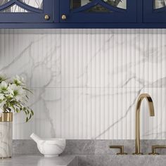 a kitchen with marble counter tops and blue cabinets, white flowers in a vase on the sink