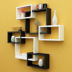 a wall mounted shelf on the side of a yellow wall with vases and other items