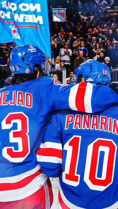 two hockey players hugging each other in front of an audience