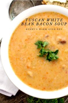 a close up of a bowl of soup on a table with bread and parsley