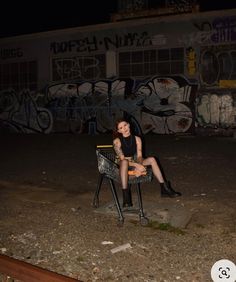 a woman sitting in a chair with graffiti on the wall behind her