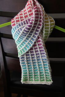 a multicolored knitted scarf sitting on top of a chair next to a green ribbon