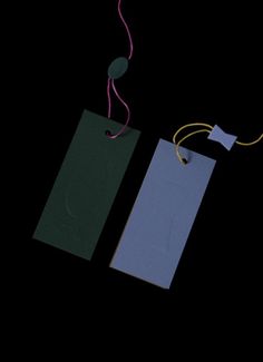 two tags with string attached to them on a black background, one is blue and the other is green